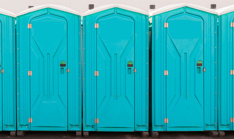 Portable-Toilets-lined-up blue portable toilets available to rent lined up