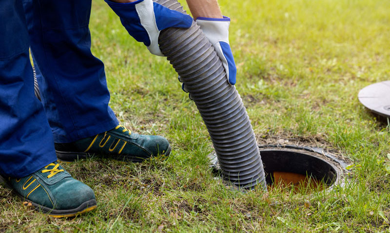 Pumping-a-septic-tank View if a man feeding hose into a septic tank.