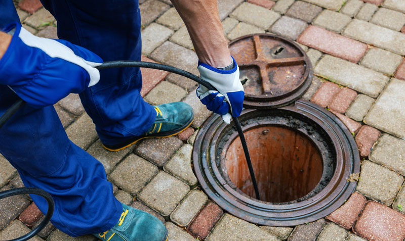 Sewer-&-Drain-Cleaning man spraying water into a sewer drain