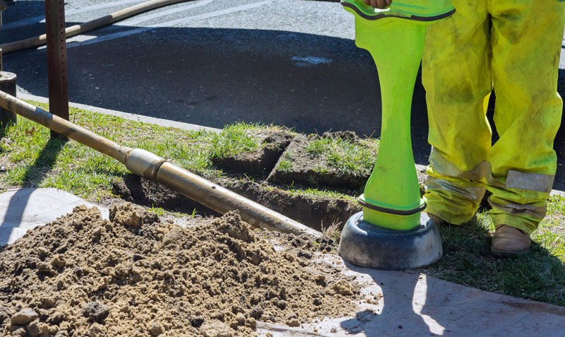 Trenchless-pipe-digging workers performing a trenchless pipe dig with a trenching machine